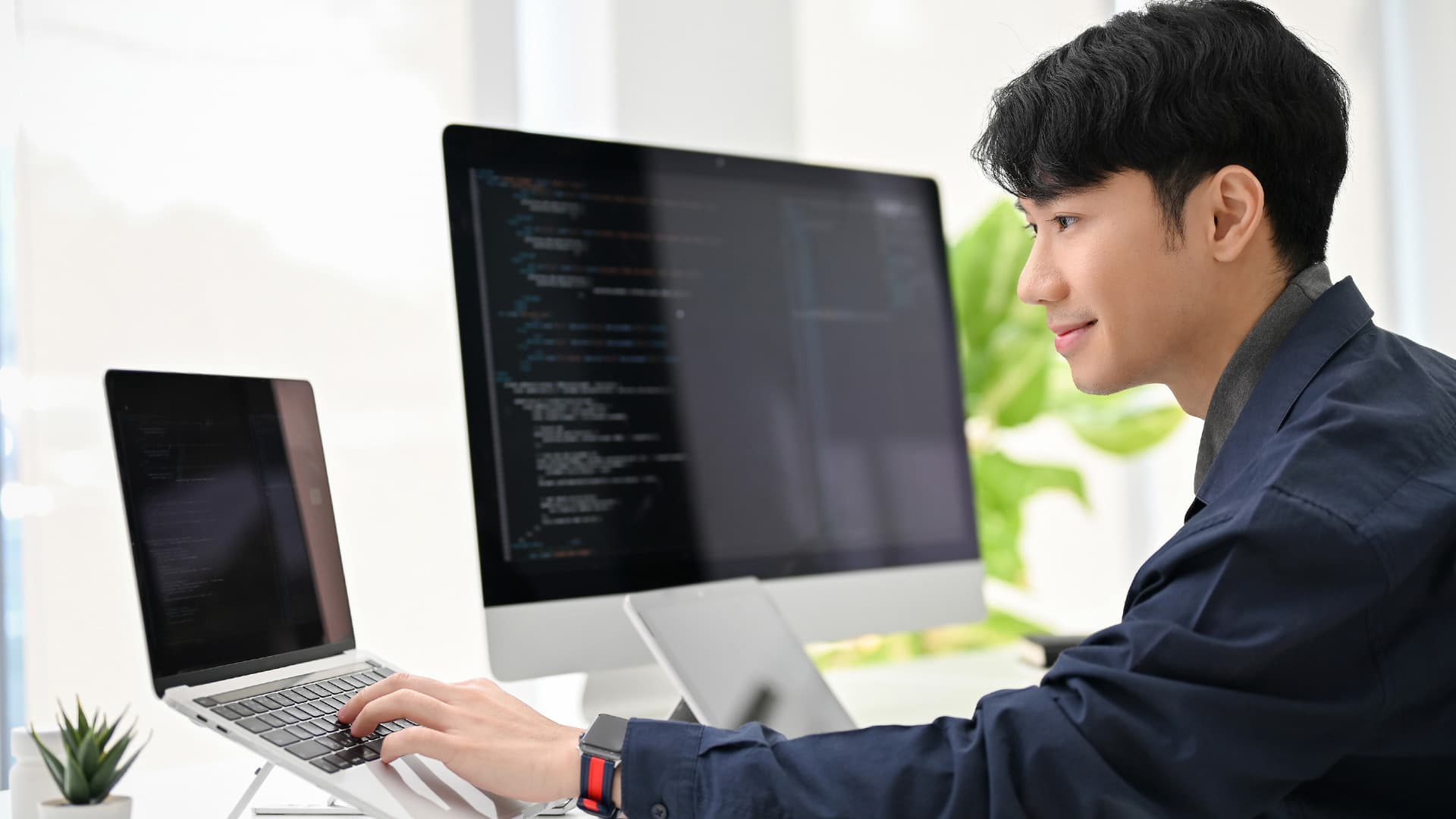 Kỹ sư trẻ viết chương trình trước hai màn hình trong văn phòng công ty Nhật